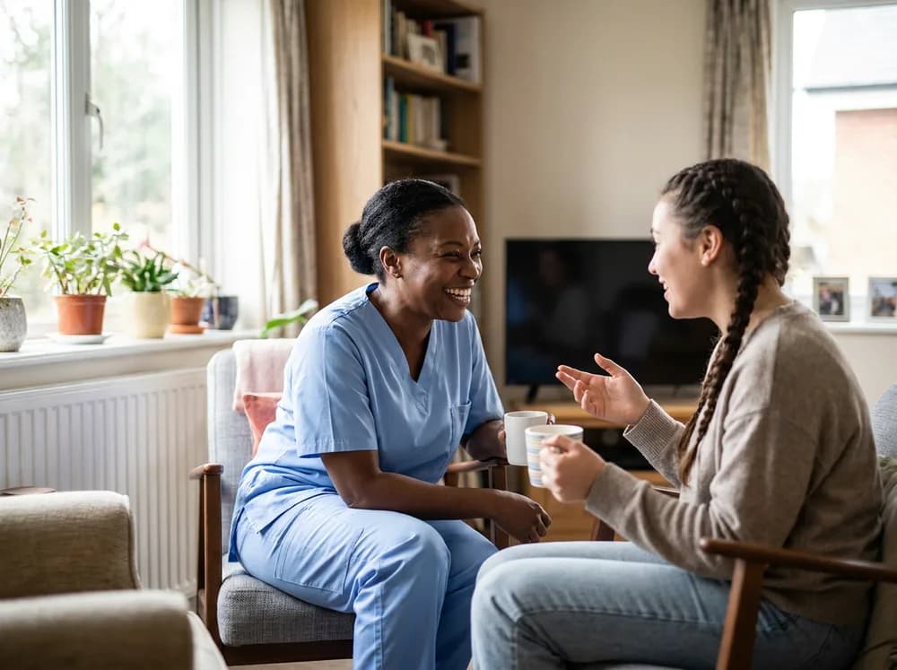 Companion caregiver playing a board game with a teenage client at the kitchen table